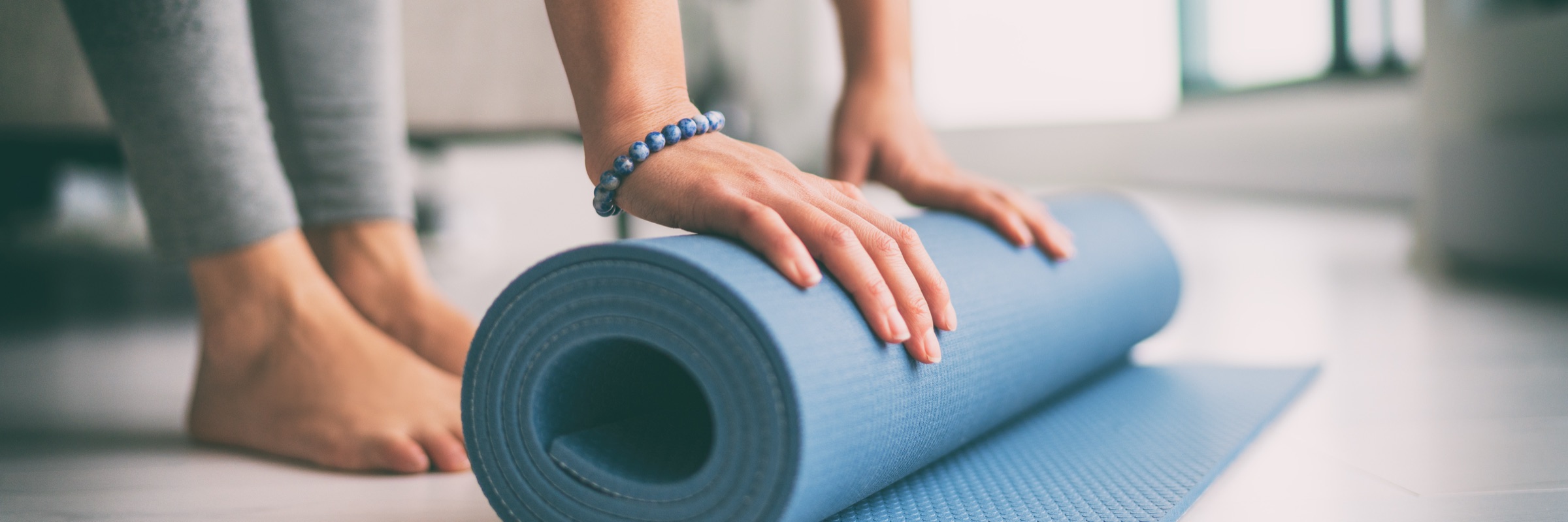 A person rolling up a yoga mat after class