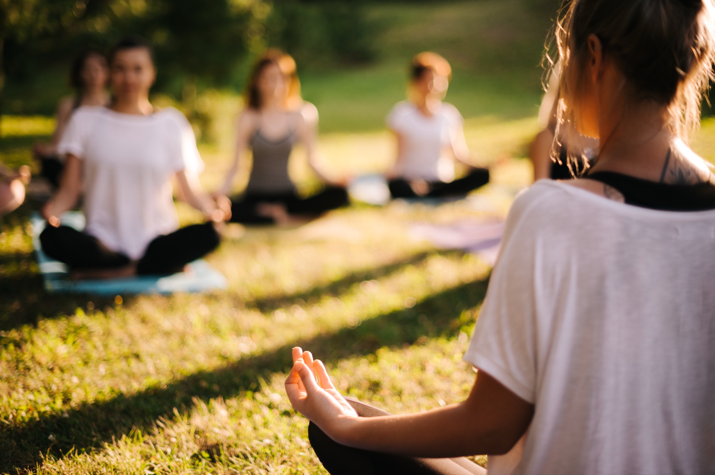 An outdoor group yoga class at golden hour, led by an instructor